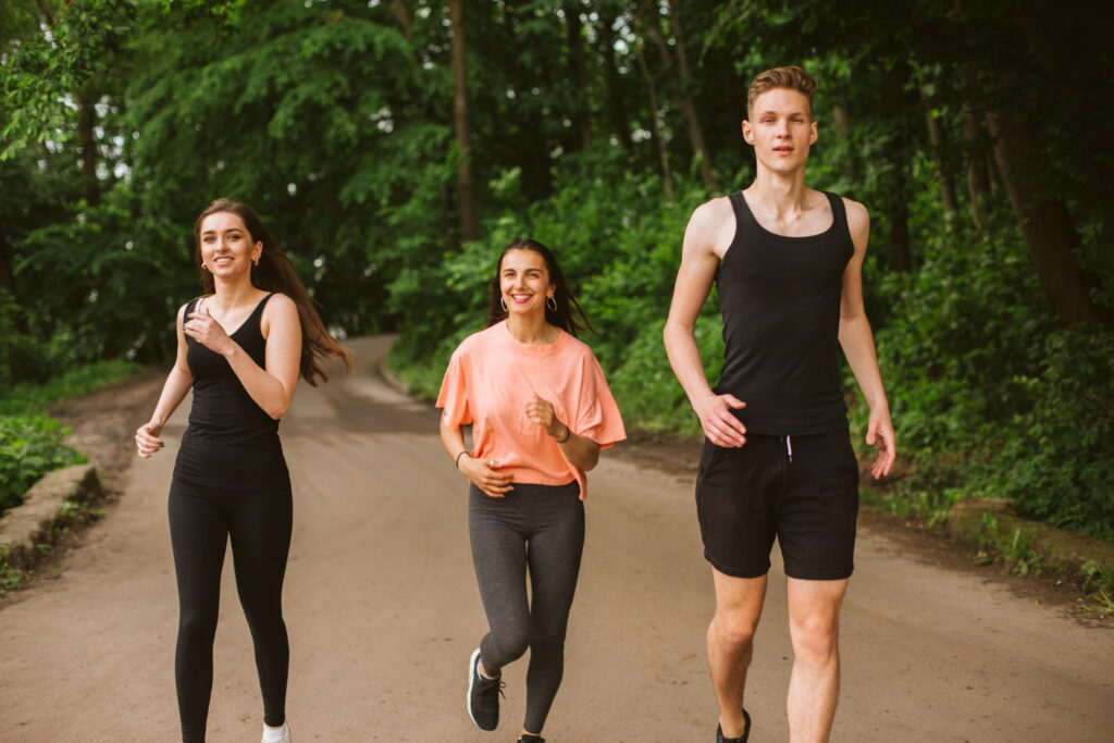 Twee vrouwen en één man zijn aan het bewegen in het bos.